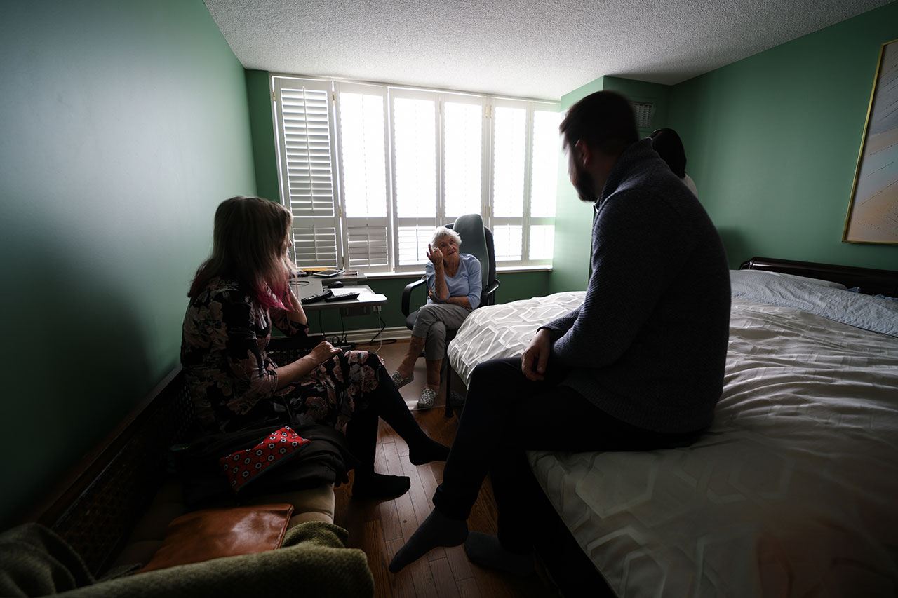 Miriam Libicki and a man listening to Rose Lipszyc talking against a bright window and green-coloured walls.