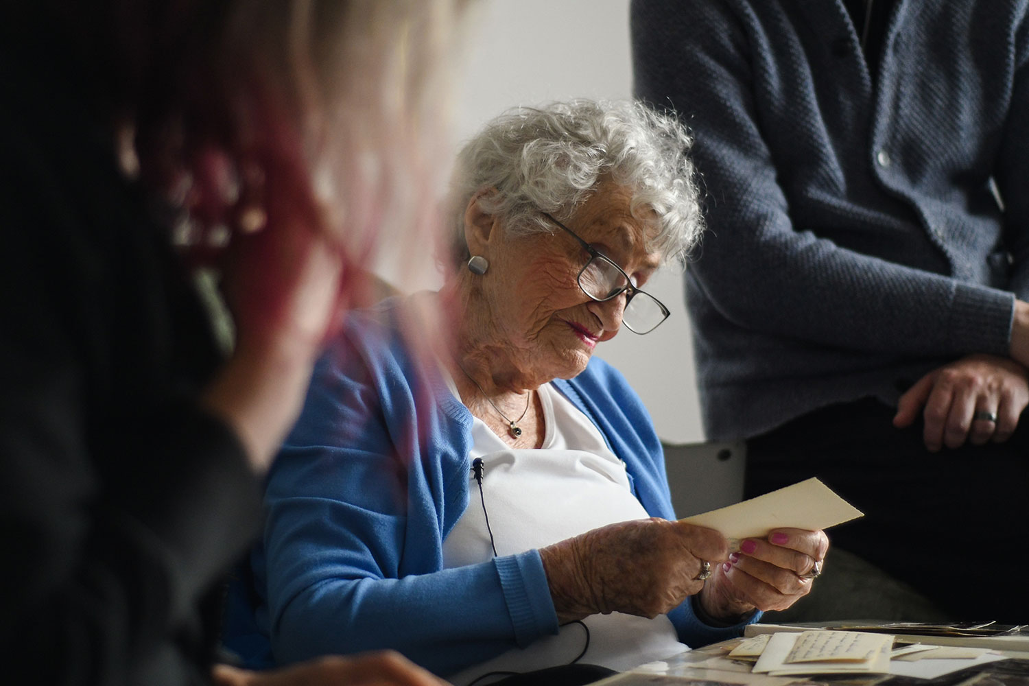 Rose Lipszyc wearing a blue cardigan and looking endearingly at a piece of paper she is holding.