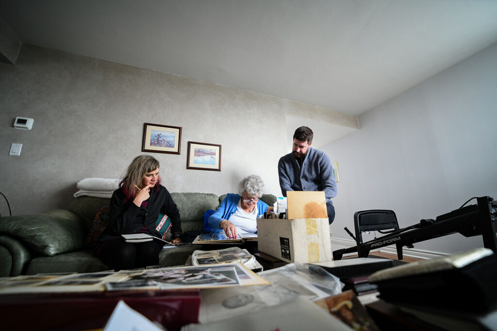 Miriam Libicki, Rose Lipszyc and a man sitting on a green couch and looking at archives.